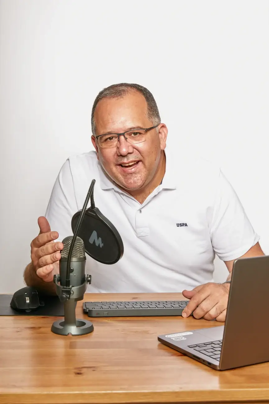 מני בן-עדי יושב ליד שולחן עם מיקרופון ומחשב נייד